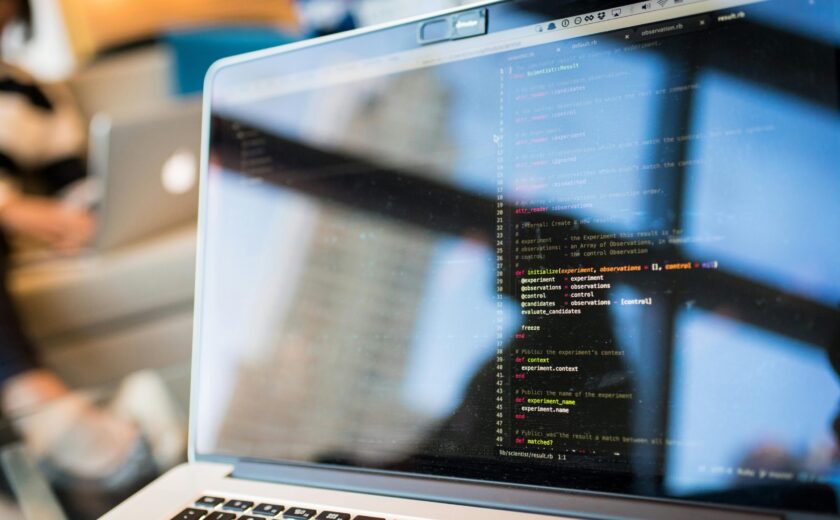 Laptop displaying code with reflection, perfect for tech and programming themes.
