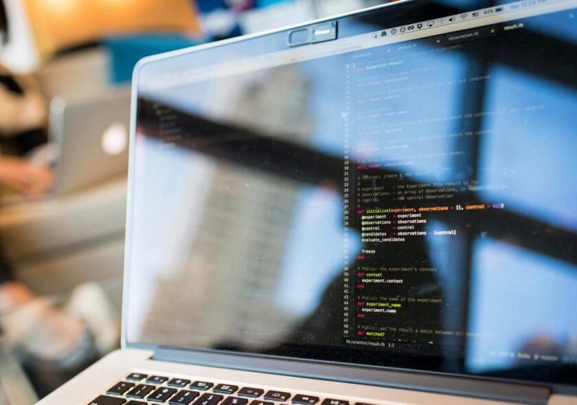 Laptop displaying code with reflection, perfect for tech and programming themes.